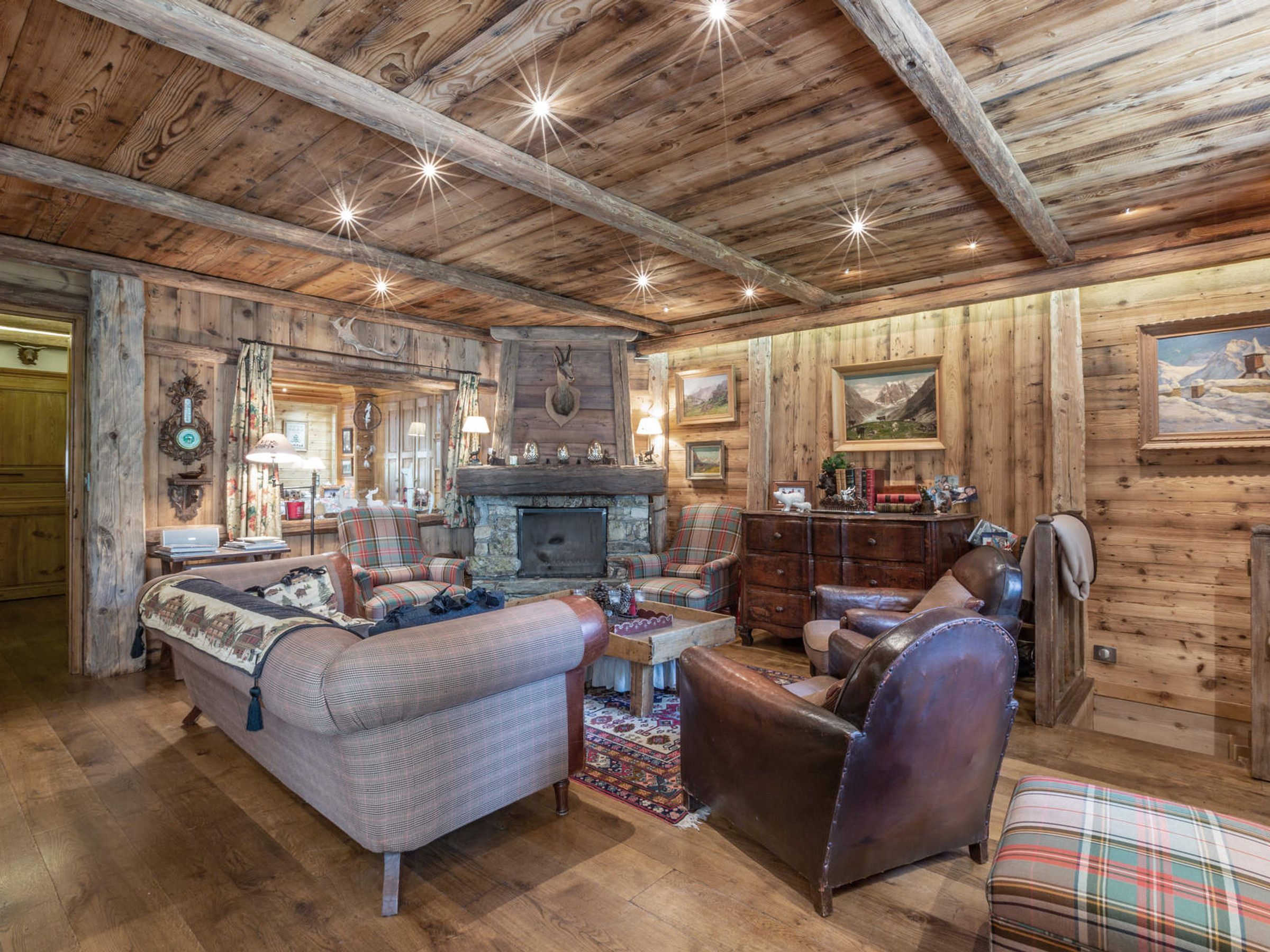 L’intérieur d’un chalet rustique, avec une cheminée, des meubles à motifs écossais et des murs en bois.