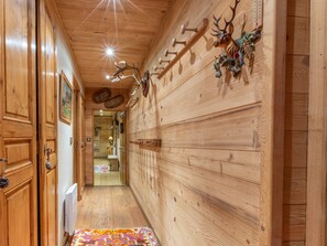 A wooden hallway with a deer head decoration, a radiator, and a patterned rug.