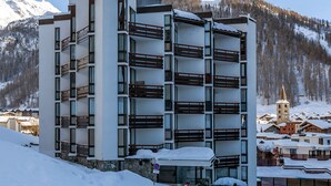 Un hotel de varios pisos con balcones, con vistas a una montaña nevada.