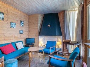 A cozy cabin interior with a wooden wall, a blue sofa, a small table, and two blue armchairs. - Charming 2BR with balcony, Wifi, pets allowed in central Val-d'Isère (Val-d'Isère)