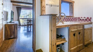 A wooden interior with a kitchen area, wooden cabinets, and a dining area with a view. - Charming 3-Room Apartment with WiFi, Ski Shuttle Access, Mountain Views (Val-d'Isère)