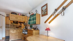 Une cuisine chaleureuse avec des meubles de rangement en bois, une table à manger et une lampe rouge.
