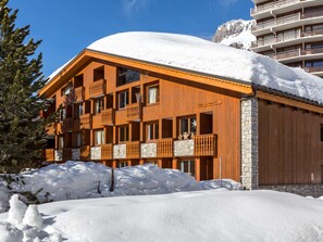 A wooden chalet with balconies and a stone facade, surrounded by snow. - Cozy duplex in Val-d'Isère with wifi and parking, pets allowed (Val-d'Isère)