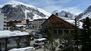Uma cidade montanhosa coberta de neve, com edifícios de madeira, uma loja de aluguel de esquis e um estacionamento.