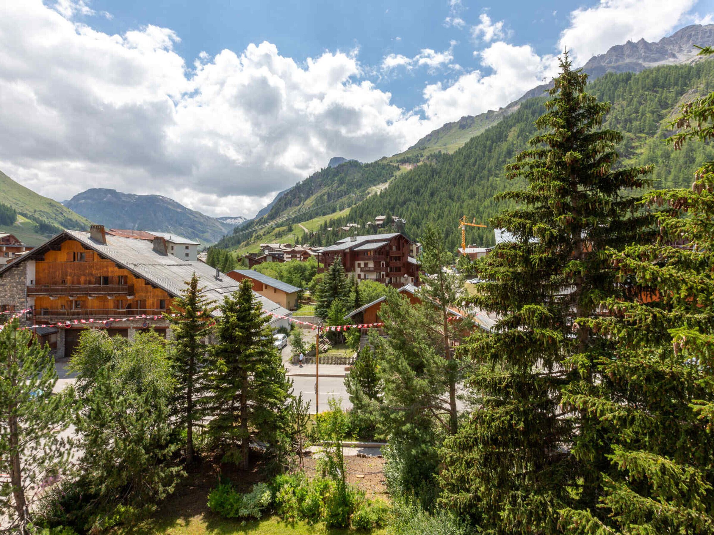 A mountain village with traditional wooden houses, a clear sky, and lush greenery.