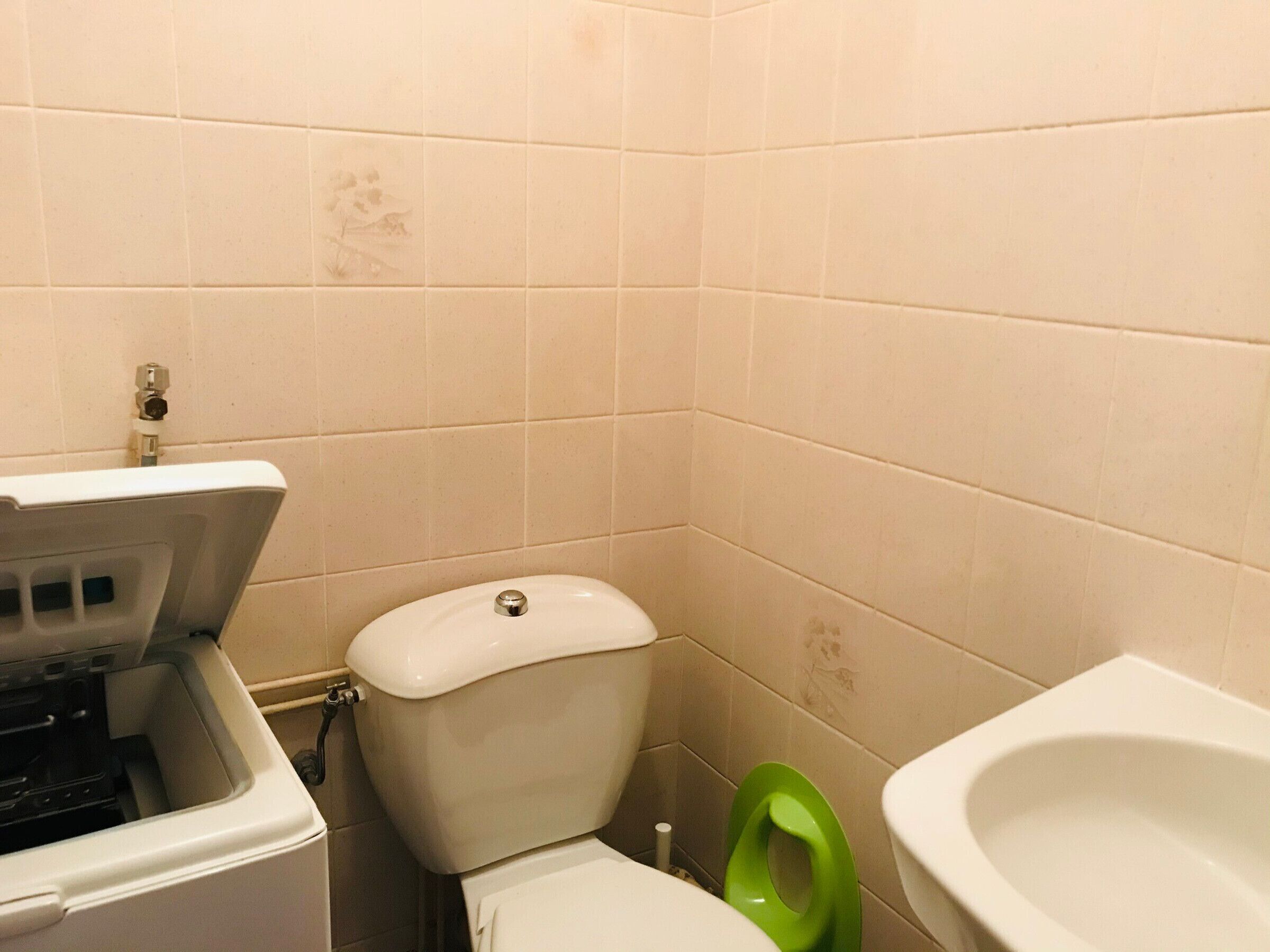 A bathroom with a toilet, a green bidet, and a sink.