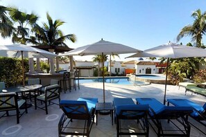 A poolside area with lounge chairs, umbrellas, and a pool.