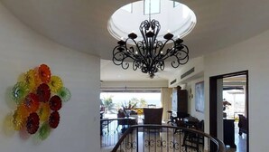 Um interior espaçoso com uma escadaria imponente, um candelabro e vista para o exterior.
