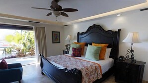 Quarto com cama grande, ventilador de teto, mesa de cabeceira com abajur e vista para o exterior.