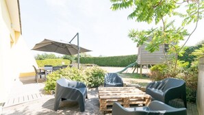 Une terrasse extérieure avec une plateforme en bois, une table et quatre chaises.