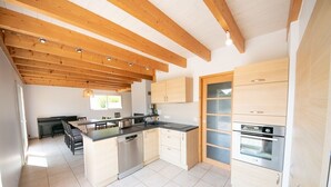 Une cuisine moderne avec des poutres en bois, un îlot central et des appareils électroménagers intégrés.