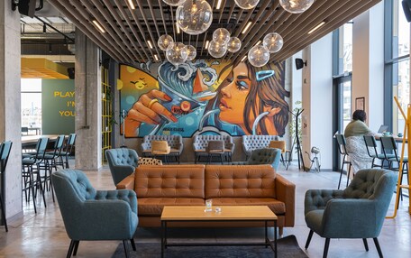 A modern lounge area with a large mural, comfortable seating, and a view of the city.