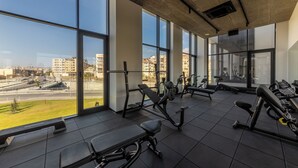 A gym with large windows, exercise equipment, and a view of the city.
