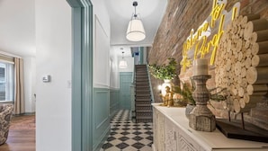 Un pasillo con piso a cuadros, una escalera y una pared decorada con un arreglo de troncos de madera.