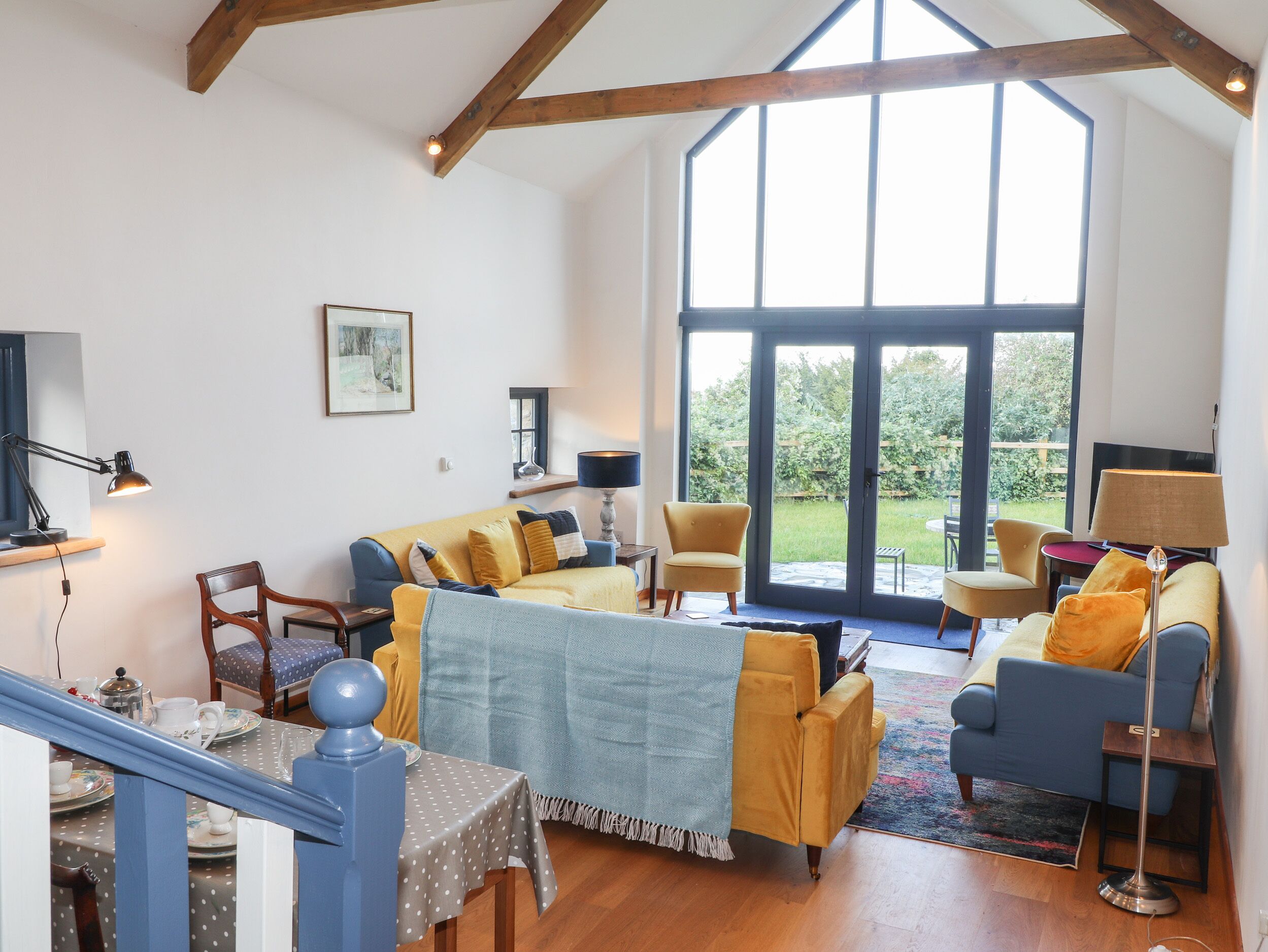 A spacious living room with a high ceiling, large windows, and a view of the outdoors.
