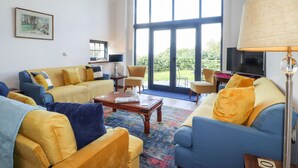 A spacious living room with a large window, a sofa set, a coffee table, and a television. - Mill Cottage (Newport)