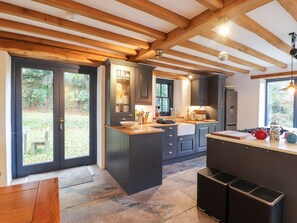 A modern kitchen with dark cabinetry, a central island, and a stone-tiled floor.