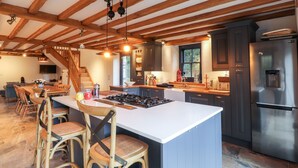 A spacious kitchen with a large island, wooden beams, and modern appliances. - Castle Coach House (Newport)