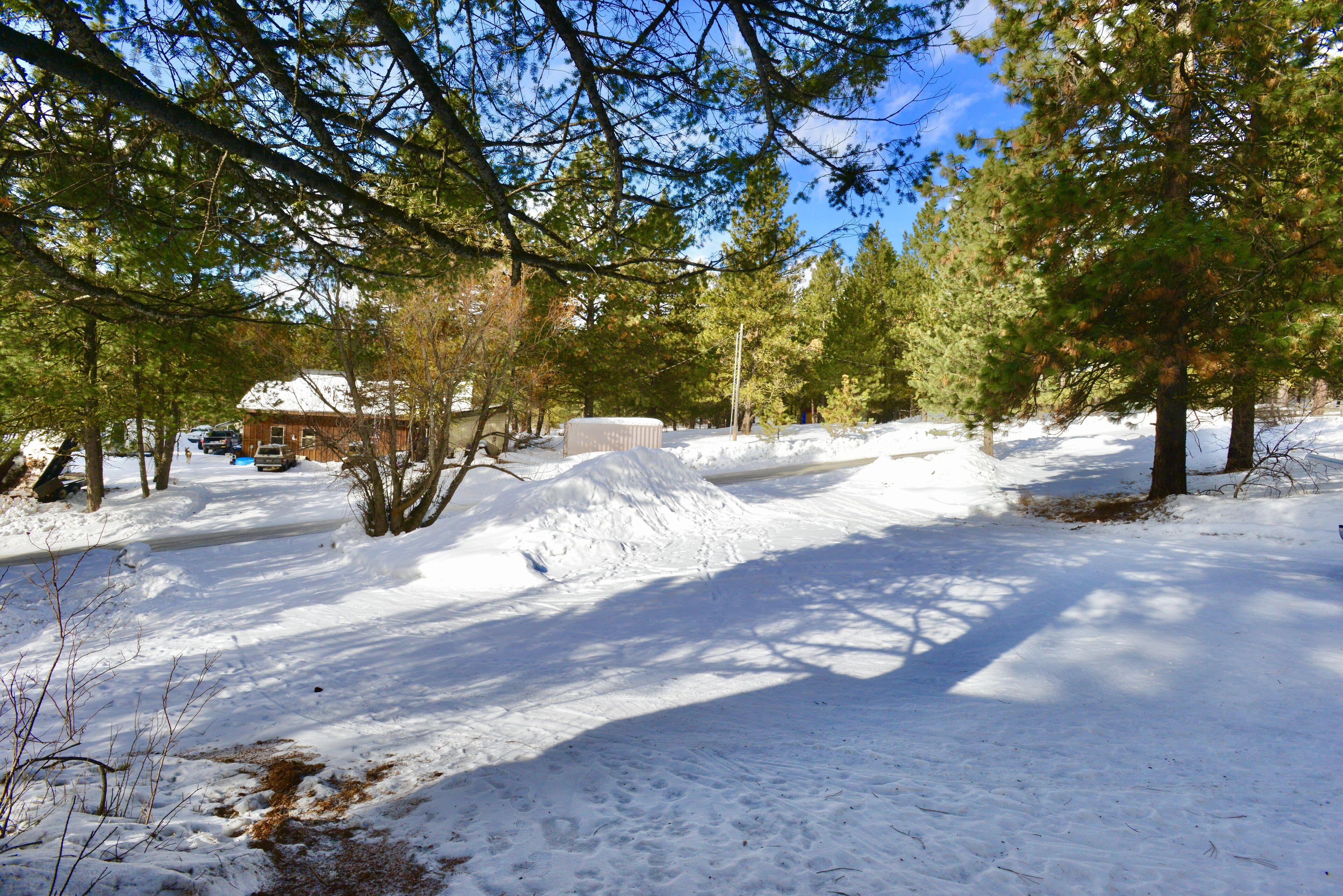 A snow-covered landscape with a wooden cabin and a large pile of snow in the foreground.