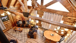 A log cabin interior with a cozy living area, wooden furniture, and a dining table.