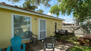 A backyard with a barbecue grill, two plastic chairs, a picnic table, and a wooden fence. - Coastal Soul by Miss Kitty’s (Aransas Pass)
