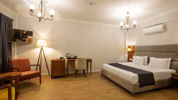 Een hotelkamer met een bed, bureau, stoel en twee kroonluchters.
