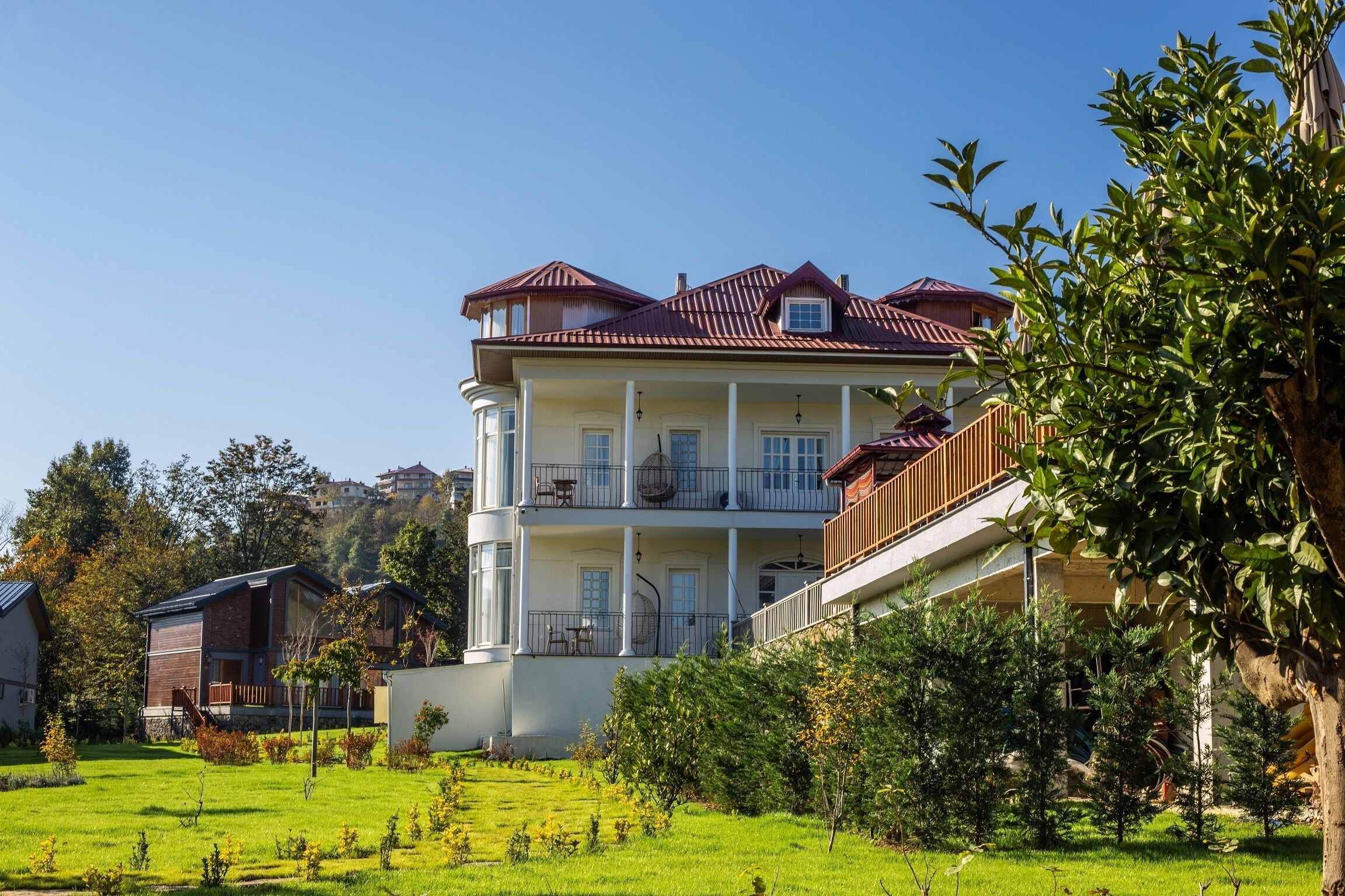 A multi-story building with a balcony, surrounded by a well-maintained lawn and trees.