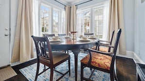 A dining area with a round table set for four, surrounded by wooden chairs with patterned cushions. - Historic Retreat in Lake Claire (Atlanta)