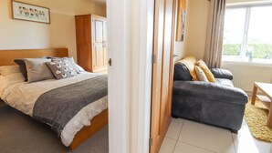 A bedroom with a bed, a wardrobe, a sofa, and a window. - Hafan Fach (Mold)
