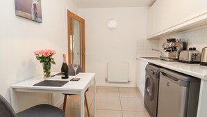 A compact kitchen with a dining area, a washing machine, and a coffee machine. - Hafan Fach (Mold)