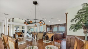 A spacious dining area with a wooden table, chairs, and a central chandelier.