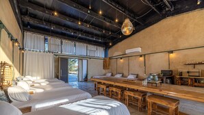 A spacious room with multiple beds, a long wooden table, and a bar area. - ibex unique Desert Inn (Ramat Negev)