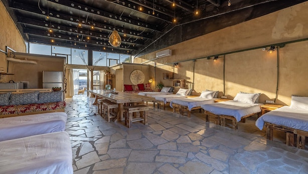 A rustic-style hotel room with a stone floor, wooden furniture, and a large dining table. - ibex unique Desert Inn (Ramat Negev)
