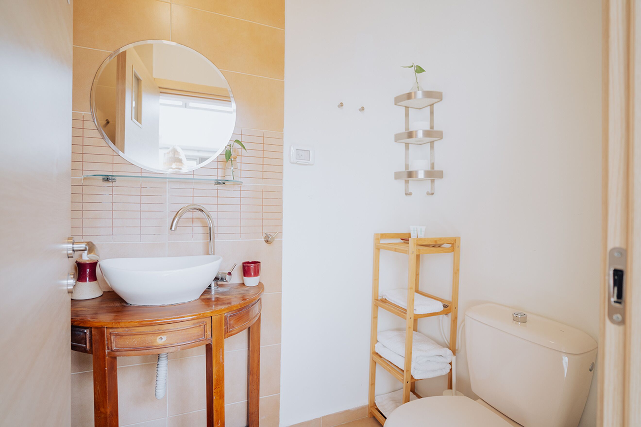 A bathroom with a wooden vanity, a white sink, a mirror, and a toilet.