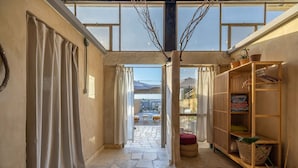 A narrow hallway with stone flooring, wooden shelves, and a view of an outdoor patio area. - ibex unique Desert Inn (Ramat Negev)