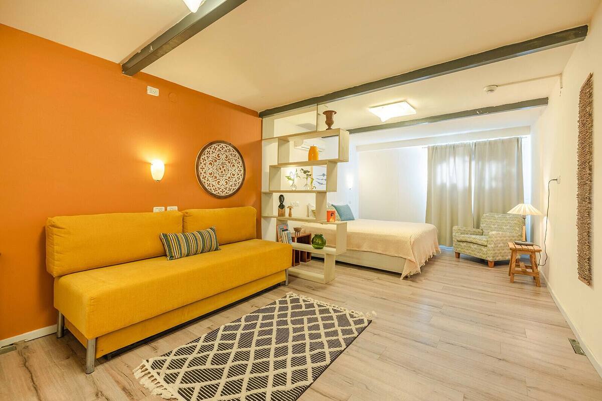 A modern living room with a yellow sofa, a coffee table, and a patterned rug.
