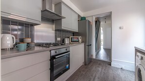 Een moderne keuken met witte kasten, een gasfornuis, een oven, een magnetron en een ingebouwde wasmachine.
