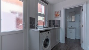 Een kleine keuken met een wasmachine, een spoelbak en een raam met gezandstraalde glass.
