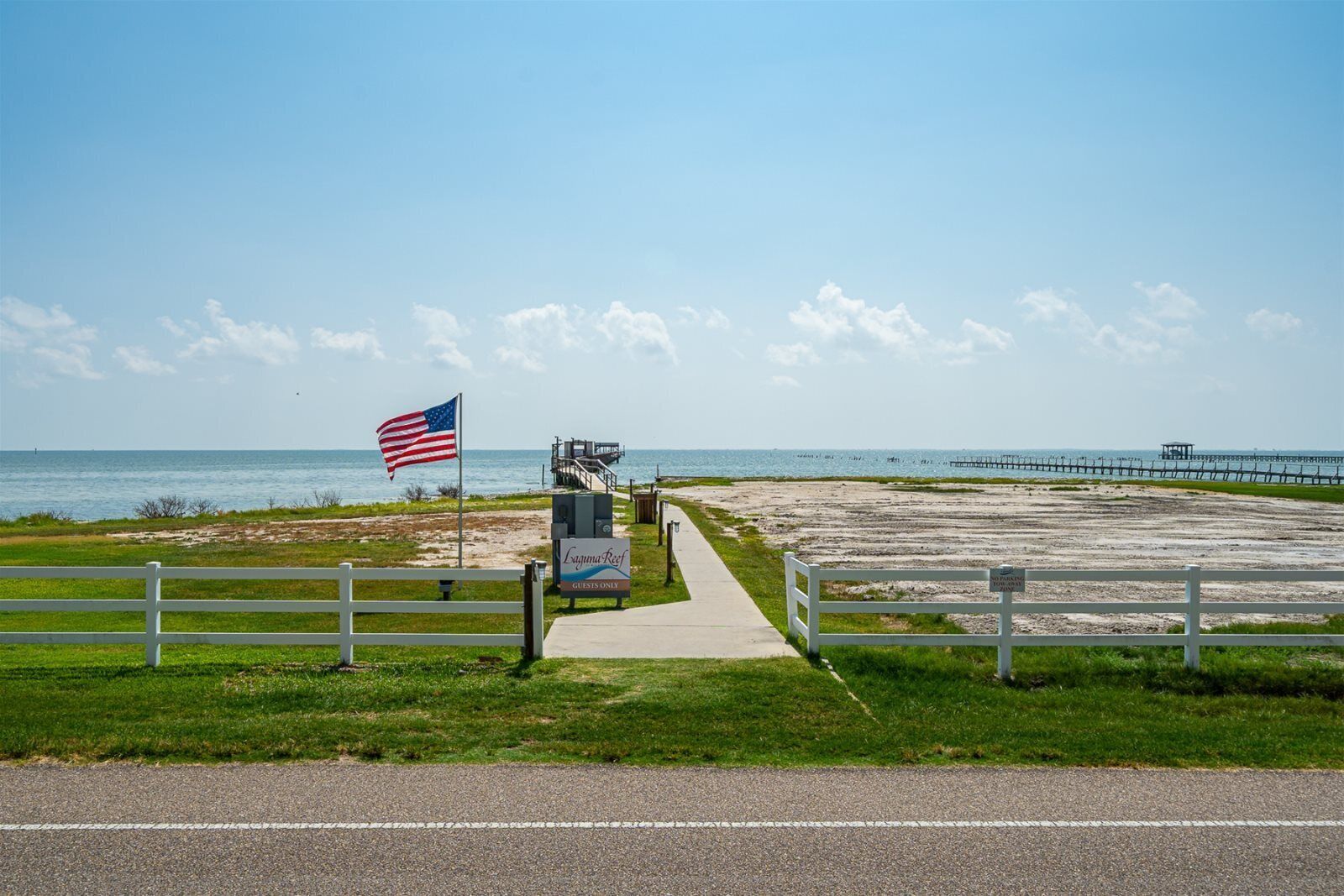 A pathway leading to a beach area with a lifeguard tower and a sign indicating 'Lighthouse Reef' and 'Guests Only'.