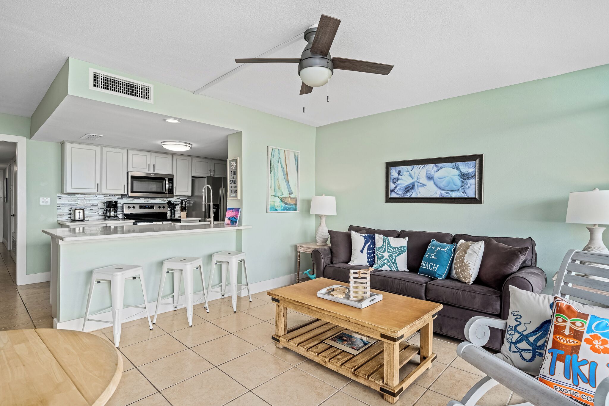 A modern kitchen with white cabinets, a central island with stools, and a dining area with a wooden table.