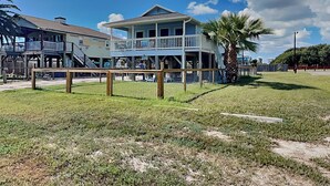 A beachfront house with a balcony, a fenced yard, and a palm tree. - Lunasea Haven by Miss Kitty’s (Rockport)