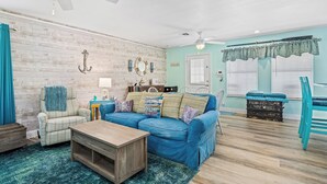 A living room with a blue sofa, wooden coffee table, and a ceiling fan. - Lunasea Haven by Miss Kitty’s (Rockport)