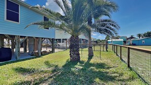 A residential area with a house, a palm tree, and a fenced yard. - Lunasea Haven by Miss Kitty’s (Rockport)