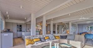 A spacious living area with a sofa, a coffee table, and a dining area with chairs.