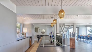 Une cuisine moderne dotée d’un îlot central, de luminaires suspendus et d’un coin repas avec des chaises et une table.