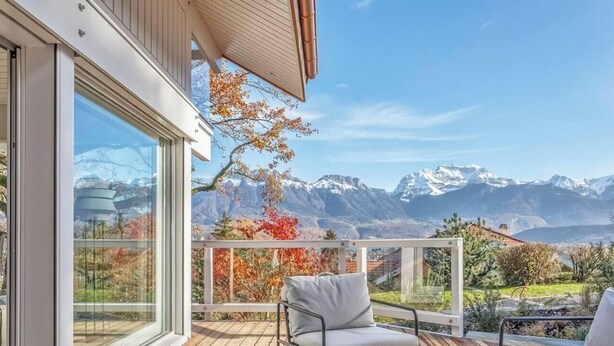 Une terrasse extérieure moderne offrant une vue sur des montagnes enneigées.