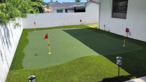 A residential property with a well-maintained lawn, a golf putting area, and a white exterior wall. - 7BR w/ Heated Pool Jacuzzi, Theatre (Pompano Beach)