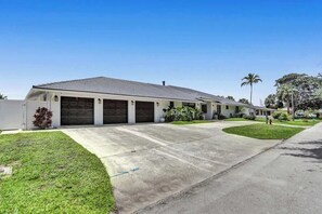 A single-story building with a garage, a driveway, and a well-maintained lawn. - 7BR w/ Heated Pool Jacuzzi, Theatre (Pompano Beach)