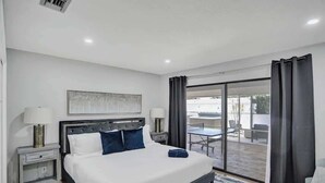 A modern hotel room with a large bed, a desk, and a view of the outdoor area. - 7BR w/ Heated Pool Jacuzzi, Theatre (Pompano Beach)