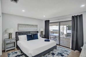 A modern hotel room with a large bed, a desk, and a view of the outdoor area. - 7BR w/ Heated Pool Jacuzzi, Theatre (Pompano Beach)
